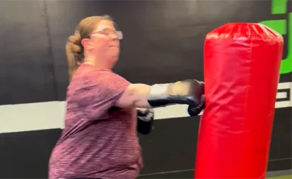Member using a punching bag during a high-energy cardio boxing workout