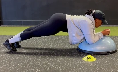 Woman holding a plank on a balance trainer during a core workout at the gym